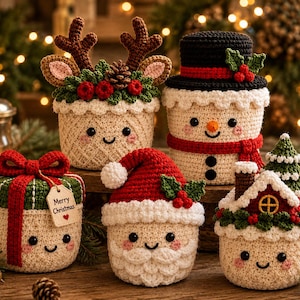May include: Five crocheted Christmas-themed containers with smiling faces. One features reindeer antlers, one is a snowman with a black hat, one is a gift box with a red bow and tag, one is a Santa Claus, and one is a house with a pine tree.