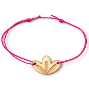 Könnte beinhalten: Ein pinkfarbenes Armband aus Schnur mit einem Holzanhänger in Form einer stilisierten Blume.
