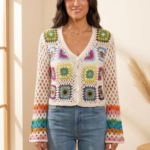 May include: A long-sleeved cardigan featuring a V-neckline and a button-front closure. The garment is constructed from cream-colored yarn with a crochet granny square pattern in various colors including green, yellow, blue, pink, and purple.