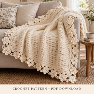 May include: A cream-coloured crochet blanket featuring a textured, grid-like stitch pattern throughout the centre. The edges of the blanket are finished with a decorative border composed of repeating three-dimensional floral motifs.