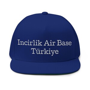 Może przedstawiać: Królewsko-niebieska czapka typu snapback z białym haftowanym napisem na przednim panelu o treści Incirlik Air Base Türkiye. Czapka posiada usztywnianą koronę, płaski daszek oraz guzik na środku góry, co zapewnia schludny i jednolity wygląd.