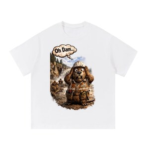 May include: A white t-shirt featuring a graphic of a brown beaver wearing a construction hard hat and a tool belt. The beaver has its hands on its head with a speech bubble above that reads Oh Dam... and a background showing a forest dam scene.