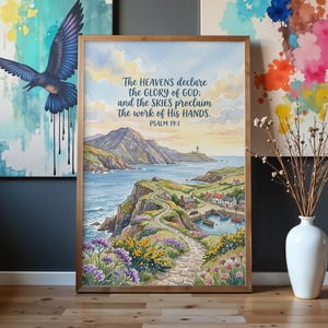 May include: A framed watercolour print featuring a coastal landscape with a stone path, green hills, a small harbour with boats, and a lighthouse. The text reads: The HEAVENS declare the GLORY of GOD; and the SKIES proclaim the work of His HANDS. PSALM 19:1.