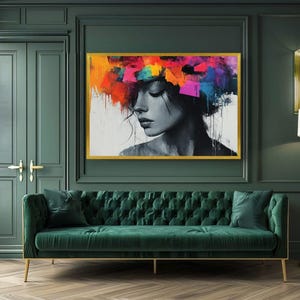 Puede incluir: Una pieza de arte mural rectangular en un marco dorado que presenta un retrato en blanco y negro de una persona con una vibrante explosión abstracta de trazos de pintura naranja, rosa, morada y azul en la parte superior, creando un contraste llamativo.