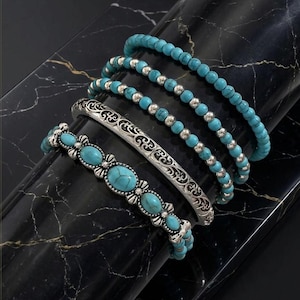 Peut inclure: Un ensemble de quatre bracelets comprenant deux rangs de perles turquoise avec des intercalaires argentés, un bracelet rigide argenté à motif gravé complexe et un bracelet orné de pierres turquoise ovales serties dans de l'argent.