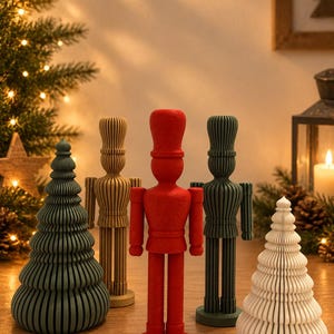 Può includere: Una collezione di figure decorative che include tre soldati schiaccianoci in piedi in rosso, verde scuro e beige, insieme a due alberi di Natale stilizzati in verde scuro e bianco, tutti caratterizzati da un design a strati, a coste e testurizzato.