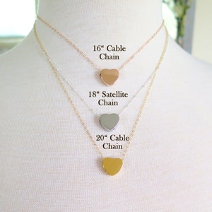 May include: Three gold heart necklaces on a white mannequin. The necklaces are 16 inches, 18 inches, and 20 inches long. The 16 inch necklace is a cable chain, the 18 inch necklace is a satellite chain, and the 20 inch necklace is a cable chain.