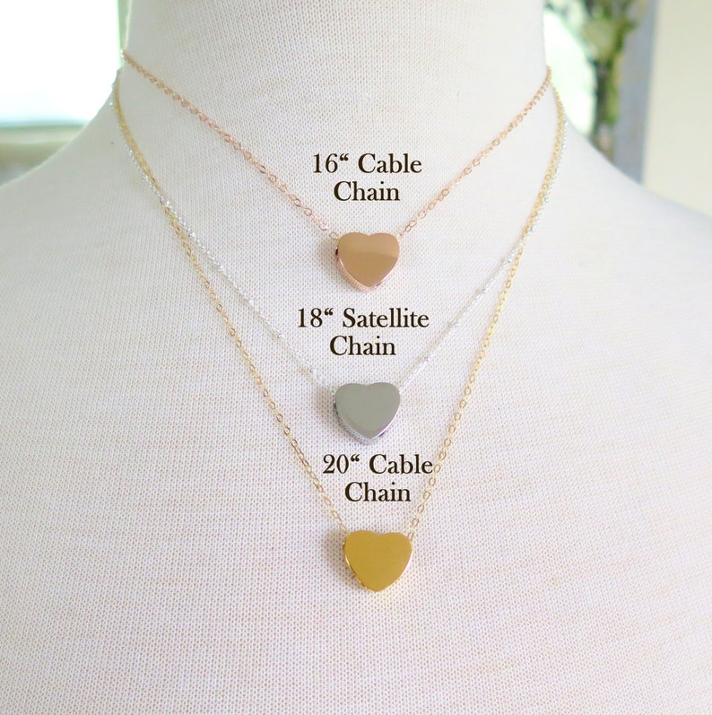 May include: Three gold heart necklaces on a white mannequin. The necklaces are 16 inches, 18 inches, and 20 inches long. The 16 inch necklace is a cable chain, the 18 inch necklace is a satellite chain, and the 20 inch necklace is a cable chain.