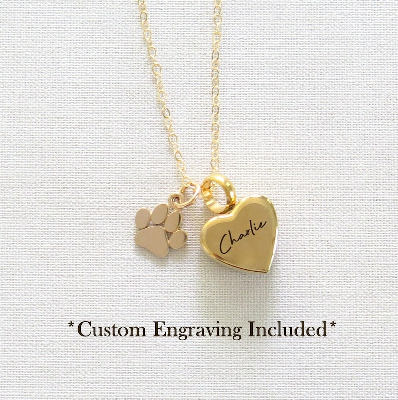 May include: Gold necklace featuring a heart-shaped pendant engraved with the name "Charlie" and a small paw print charm. Custom engraving is included.