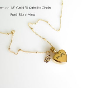 May include: Gold filled satellite chain necklace with a heart-shaped pendant engraved with the name "Murphy" and a small paw print charm. The chain is 18 inches long.
