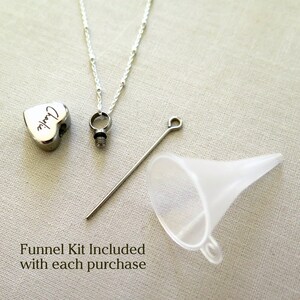 May include: A silver heart-shaped cremation necklace inscribed with the name "Charlie". The necklace is supplied with a funnel kit for filling the pendant.