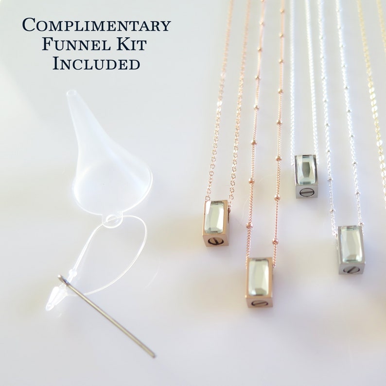 4 small rectangle urn pendants with beveled crystal fronts laying next to a complimentary funnel kit that comes with each necklace purchase.