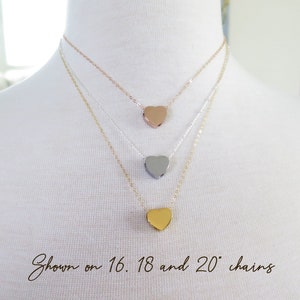 May include: Three gold heart necklaces on a white mannequin. The necklaces are shown on 16, 18, and 20 inch chains.