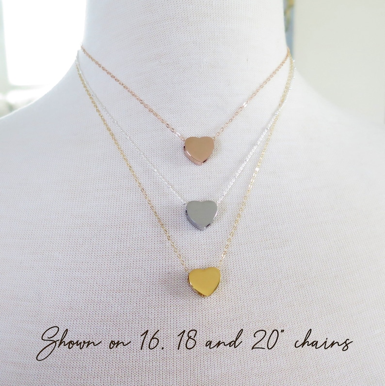 May include: Three gold heart necklaces on a white mannequin. The necklaces are shown on 16, 18, and 20 inch chains.