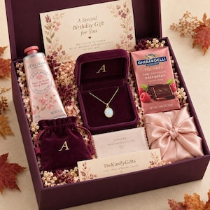 May include: A gift box containing a 30 ml L'Occitane cherry blossom hand cream, a gold necklace with an oval opal pendant in a velvet box, a Ghirardelli dark chocolate raspberry bar, a velvet pouch, a polishing cloth, and a birthday card.