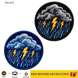 May include: A pair of circular embroidered patches featuring a storm cloud design with yellow lightning bolts and blue rain streaks. One patch has a black border and background, while the other has a blue border and background. Text reads Pair of 2.