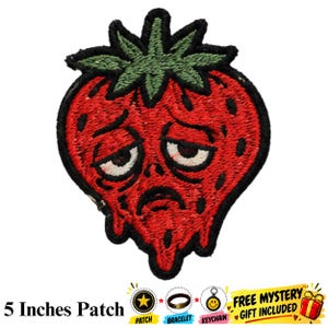 Puede incluir: Un parche bordado con forma de fresa roja y tallo verde. La fresa presenta una expresión facial triste y derretida con ojos caídos y boca hacia abajo, delineada con hilo negro. El texto 5 Inches Patch es visible en la parte inferior.