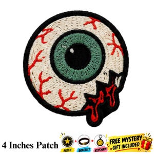 Puede incluir: Un parche bordado circular con un diseño de globo ocular realista que presenta un iris verde, una pupila negra y vasos sanguíneos rojos sobre un fondo blanco. El parche tiene un borde negro y una sección roja dentada y goteante.