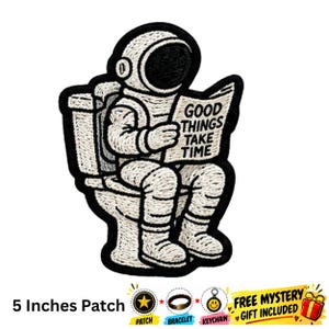 Op de afbeelding: Een geborduurde patch met een astronaut die op een toilet zit en een krant leest met de tekst GOOD THINGS TAKE TIME. De patch is 12,7 cm groot en heeft een zwarte rand, met witte en crèmekleurige draaddetails door het hele ontwerp.