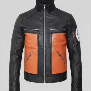 Puede incluir: Una chaqueta de cuero negra y naranja con cuello alto acanalado, cremallera frontal plateada de longitud completa, dos bolsillos horizontales en el pecho con cremalleras y dos bolsillos inferiores inclinados. Un parche blanco en la manga.
