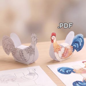 Könnte beinhalten: Zwei Hahnfiguren aus Papier, eine in Schwarz-Weiß-Kontur und eine farbig in Rot, Gelb und Blau, neben zwei flachen, bedruckten Papierbögen mit denselben Hahnmotiven. Der Text .PDF ist in der oberen rechten Ecke zu sehen.