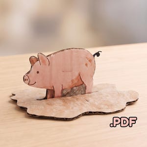 Könnte beinhalten: Eine rosa Schweinefigur aus geschichtetem Karton, die aufrecht auf einer passenden, braun strukturierten Kartonbasis steht. Die Figur zeigt ein einfaches gezeichnetes Design mit einem kleinen Kringelschwanz auf einer flachen Oberfläche. Der Text .PDF ist sichtbar.