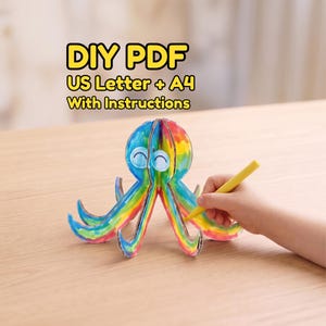 Può includere: Un progetto di bricolage in carta 3D a forma di polpo con strisce color arcobaleno e due occhi circolari. Il testo sopra recita DIY PDF US Letter + A4 With Instructions. Il polpo è composto da pezzi di cartone a incastro ed è in fase di colorazione.