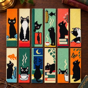 May include: A set of twelve rectangular bookmarks featuring cross-stitch style illustrations of black and tuxedo cats in various scenes, including cats with books, coffee cups, fish, butterflies, and windows, rendered in vibrant colors on a grid pattern.
