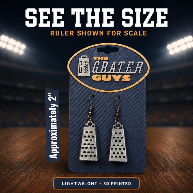 May include: A pair of silver-colored cheese grater earrings on a dark blue display card labeled The Grater Guys. The earrings feature a textured metal design with hook-style backings. The card indicates the items are approximately 2 inches in size.