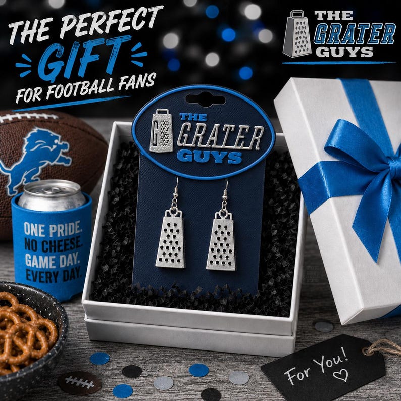 May include: A pair of silver-toned cheese grater earrings displayed on a dark blue branded card labeled The Grater Guys, presented in a white gift box with a blue ribbon, alongside a football, a blue can cooler, and a bowl of pretzels.