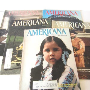 May include: A collection of five vintage Americana magazines featuring various cover photographs, including a portrait of a child in traditional attire, a person in historical clothing, and a vintage car, all with the title Americana printed at the top.