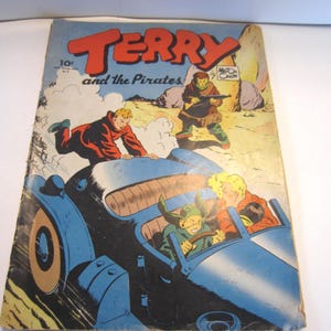 May include: A vintage Terry and the Pirates comic book featuring a blue car with three characters inside and one character leaping onto the hood. The cover displays the title in large red letters, a 10 cent price mark, and the artist name Milton Caniff.