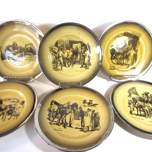 May include: Set of six vintage decorative plates with silver rims. Each plate features a sepia-toned illustration of people and horses. The plates have a yellow center and a silver rim, creating a classic aesthetic.