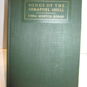 May include: A hardcover book with a dark green textured cover. The front cover features a rectangular label with a gold border containing the text SONGS OF THE SHRAPNEL SHELL and the author name CYRIL MORTON HORNE in gold capital letters.