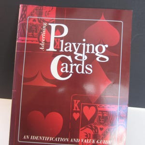 May include: A book titled "Playing Cards" with a red cover featuring white text and playing card suit symbols. The cover also includes the text "Advertising" and "An Identification and Value Guide".