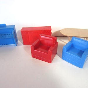May include: A collection of miniature toy furniture in primary colors. Includes a blue piano, a red chest, a red armchair, a blue armchair, and a light brown oval table.