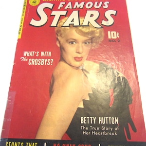 May include: A vintage comic book titled Famous Stars No. 2 featuring a portrait of Betty Hutton on a red background. The cover includes the text Exciting Life Stories of Famous Stars, What's with the Crosbys?, and The True Story of Her Heartbreak.