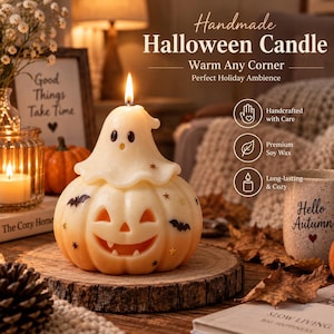 Può includere: Una candela in cera color crema a forma di zucca con un fantasma sopra. La zucca presenta un volto intagliato da lanterna, sagome di pipistrelli neri e piccoli accenti a forma di stella dorata. Uno stoppino è acceso sulla cima del fantasma.