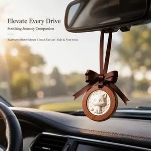 Op de afbeelding: Een ronde auto-luchtverfrisser die aan een achteruitkijkspiegel hangt met een bruin lint. Het heeft een houten frame, een bruine satijnen strik en een wit cirkelvormig midden met een reliëf van een kat. Tekst: Elevate Every Drive, Soothing Journey Companion, Rearview Mirror Mount, Fresh Car Air, Safe & Non-toxic.