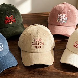 Könnte beinhalten: Fünf Baseballkappen aus Cord in verschiedenen Farben wie Dunkelgrün, Blau, Beige, Rosa und Creme. Jede Kappe ist mit Text bestickt: Merry Christmas, DAD EST. 2025, YOUR CUSTOM TEXT, Today is a good day und Bride in verschiedenen Schriftarten.
