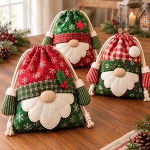 May include: Three fabric drawstring gift bags designed to resemble gnomes. Each bag features a white felt beard, a round nose, and festive patterns including red and green colors, snowflake prints, plaid accents, and small holly berry details.