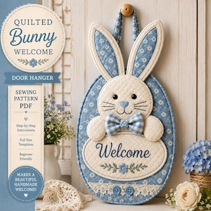 May include: A quilted bunny door hanger featuring blue and white floral fabric, a cream-colored face, a blue gingham bow tie, and a heart-shaped nose. The oval base displays the word Welcome in blue script above a small floral embroidery detail.
