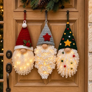 "Crochet gnome ornament bundle with fairy lights glowing in all three beards - Santa, gray, and green tree hat gnomes on wooden door