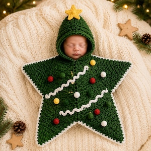 May include: A star-shaped crochet baby swaddle in dark green with a hood topped by a yellow star. The garment features white wavy trim, small red, yellow, white, and dark green pom-poms, and a white crocheted border along the outer edges.