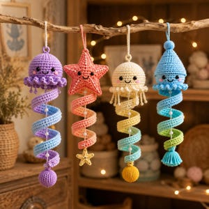 May include: Four hanging crochet ornaments suspended from a wooden branch. The set includes a purple jellyfish, a coral starfish, a cream-colored jellyfish, and a blue jellyfish, each featuring a long, spiraling tail and small decorative beads.