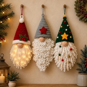 May include: Three hanging crochet gnome ornaments with pointed hats. The left gnome has a red hat with holly, the center a gray hat with a red star, and the right a green hat with a yellow star and small pom-poms. All have white beards.