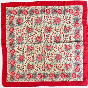 May include: A square scarf featuring a vibrant red border surrounding a cream-colored center. The fabric is decorated with a repeating pattern of pink roses and small red berries, accented by muted green leaves and thin, winding stems throughout.