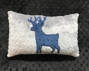 May include: A gray plush pillow with a blue embroidered deer silhouette.