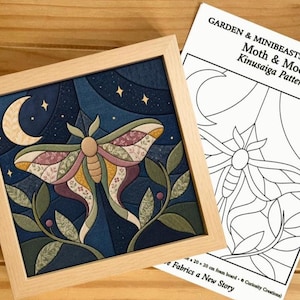 May include: A square wooden frame containing a fabric Kinusaiga art piece of a moth and crescent moon, accompanied by a printed paper pattern titled Garden & Minibeasts Collection Moth & Moon Kinusaiga Pattern with 20 x 20 cm dimensions.
