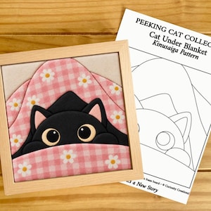 Puede incluir: Una pieza de arte Kinusaiga enmarcada que muestra un gato negro con ojos grandes asomándose bajo una manta de cuadros vichy rosa y blanco con estampado de margaritas, junto a un patrón de papel titulado PEEKING CAT COLLECTION Cat Under Blanket.